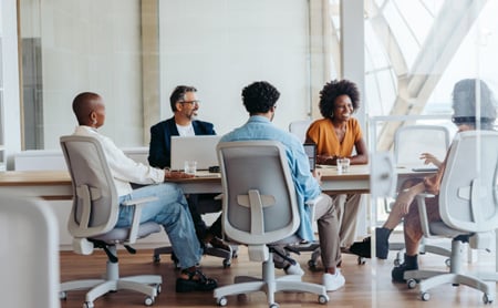 Coworkers sit at a conference table and talk cheerfully