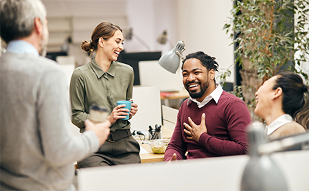 Coworkers in an office bullpen laugh together