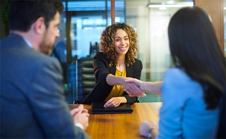 A job candidate shakes hands with an interviewer during a panel interview