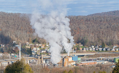 Industrial buildings wtih smoke pouring out in a residential area.