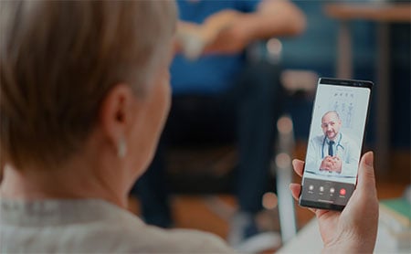 A person holding a smartphone participating in a telehealth appointment.